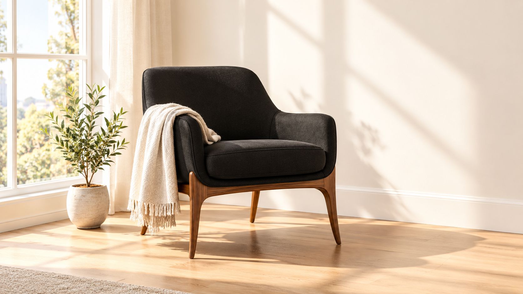 A modern black accent chair with a soft throw blanket beside a potted plant in a room.